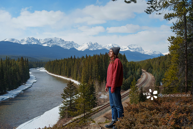 女人凝视着被森林环绕的铁路和河流图片素材