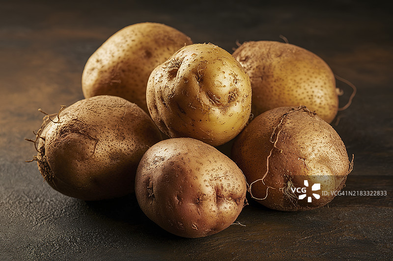 质朴的土豆放在深色纹理背景上图片素材