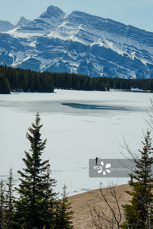在冰封的山湖上行走的男子用智能手机拍照图片素材
