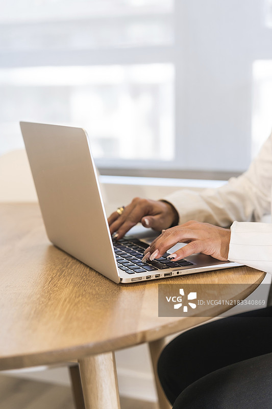 垂直照片，特写一位女商人在木桌上使用笔记本电脑的双手图片素材