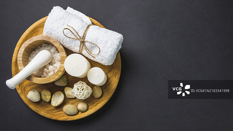 高视角盐、毛巾、蜡烛、水疗石、木盘与黑色背景图片素材