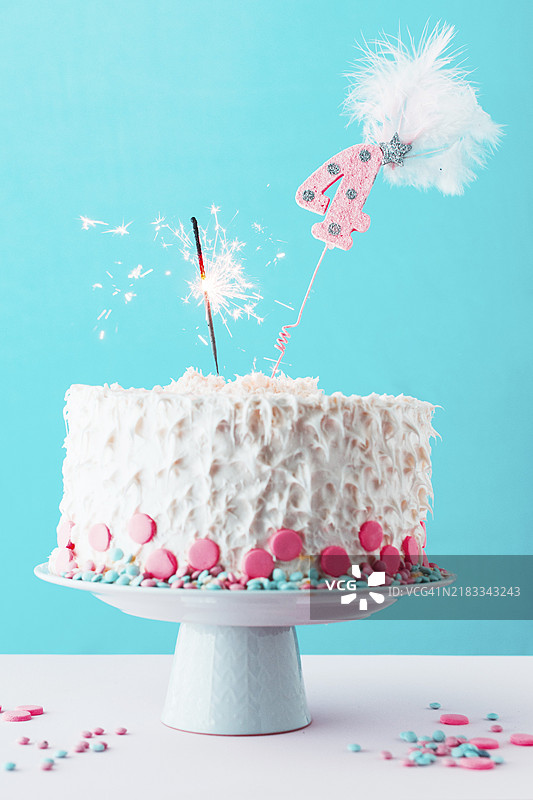 四岁生日蛋糕上点燃的烟花，白色表面图片素材