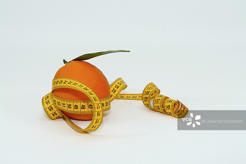 新鲜橙子与叶子被卷尺环绕，孤立在白色背景上，留有空白空间。图片素材