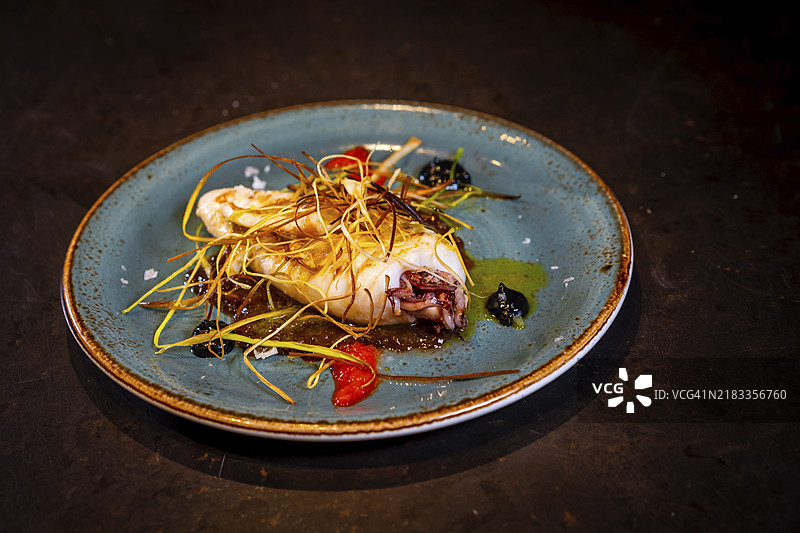 黑色背景上的炸鱿鱼，放在绿色盘子里，配有酱汁图片素材