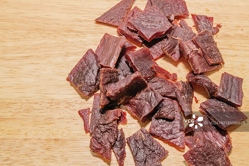 木质背景上的小块加工牛肉干图片素材