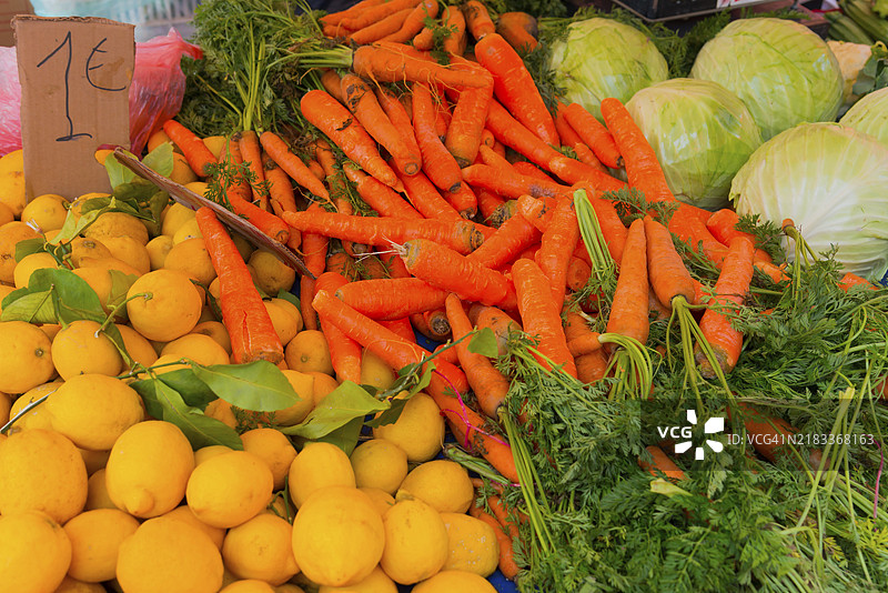市场摊位上摆放着新鲜的蔬菜，如胡萝卜、柠檬和卷心菜。价格标签显示商品的价格，市场，纳夫普利翁，阿戈利斯，伯罗奔尼撒，希腊，欧洲。图片素材