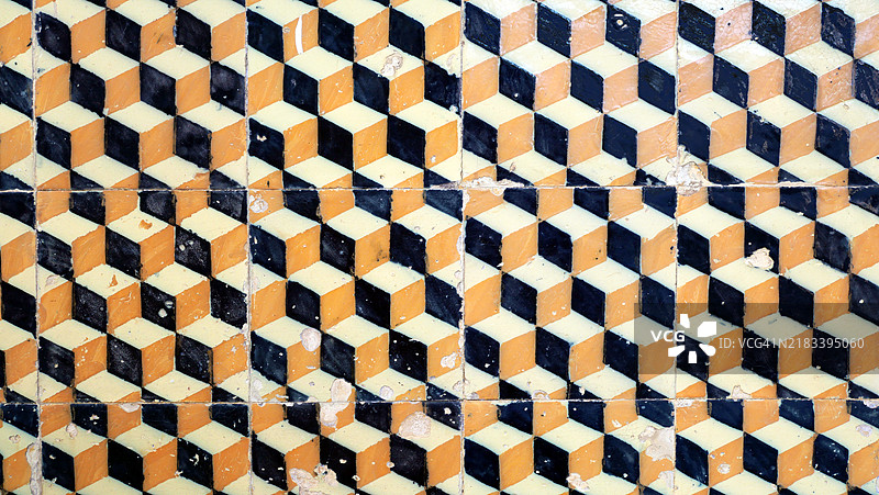 波尔图一栋房屋外立面的水泥瓷砖特写,呈现黄色、黑色和白色的几何图案。阳光照射下,自然色彩和风化效果。图片素材