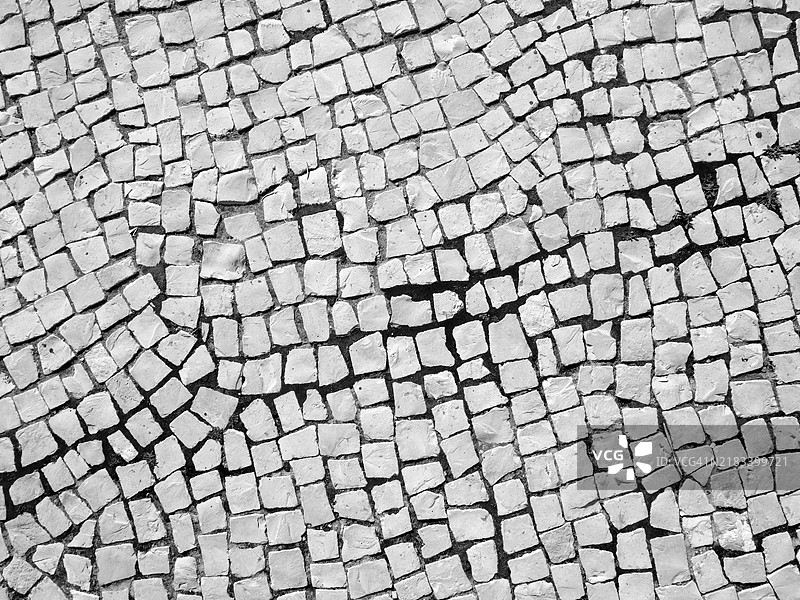 不规则且干净的白色铺路石。葡萄牙波尔图的人行道特写。粗糙的纹理。阳光。黑白色调。图片素材