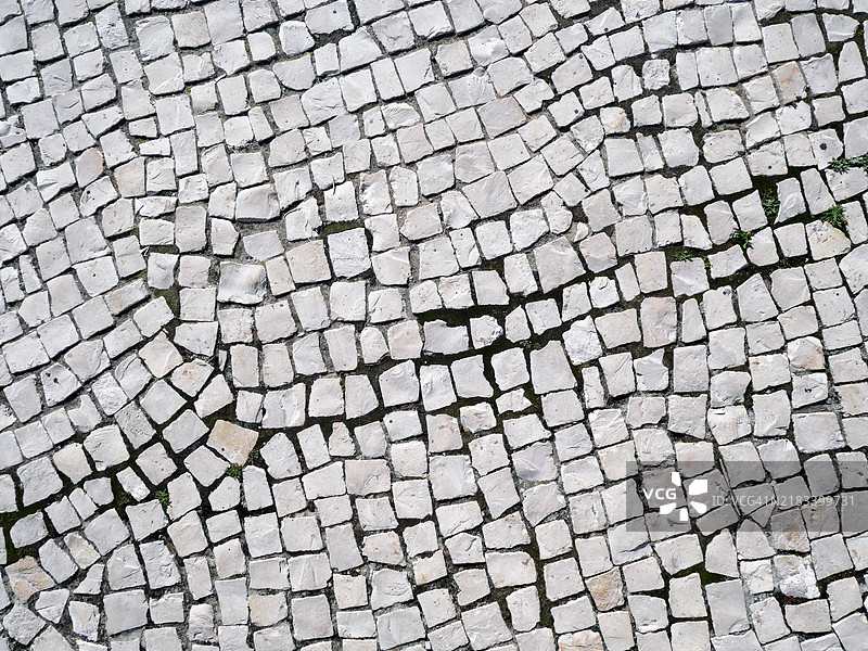 波尔图不规则白色铺石人行道的特写。粗糙的纹理。阳光。自然色彩和风化。图片素材
