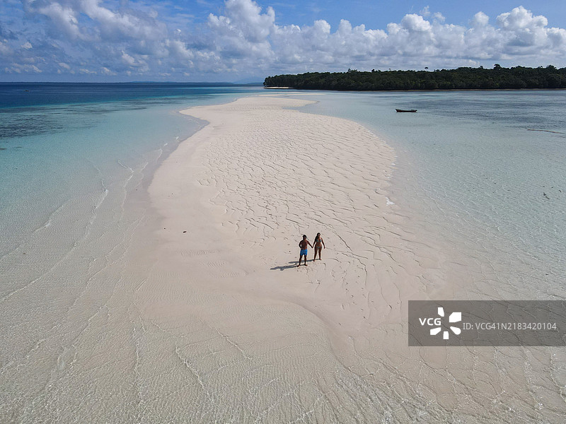 情侣在热带水域的孤立沙洲上散步图片素材