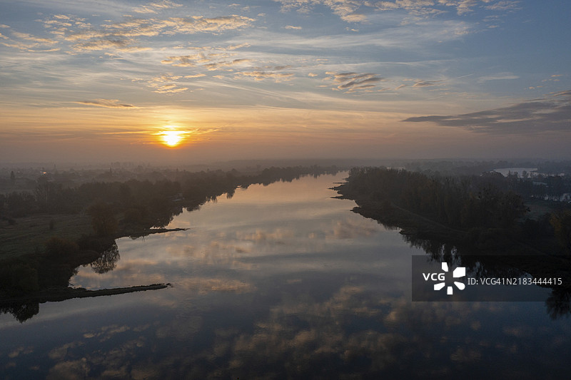 德国萨克森-安哈尔特州马格德堡的易北河日出，水面倒映着天空中的云彩。图片素材