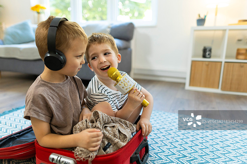 两个白人兄弟在为家庭旅行打包行李时玩耍图片素材