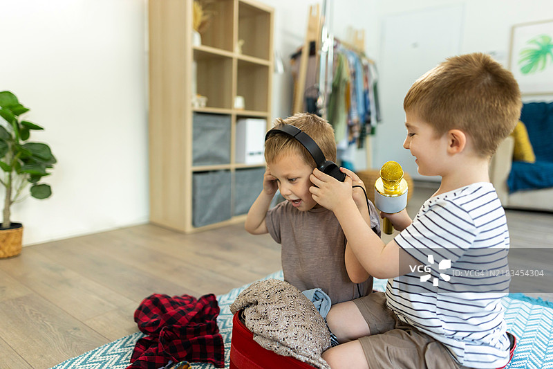 两个白人兄弟在为家庭旅行打包行李时玩耍图片素材