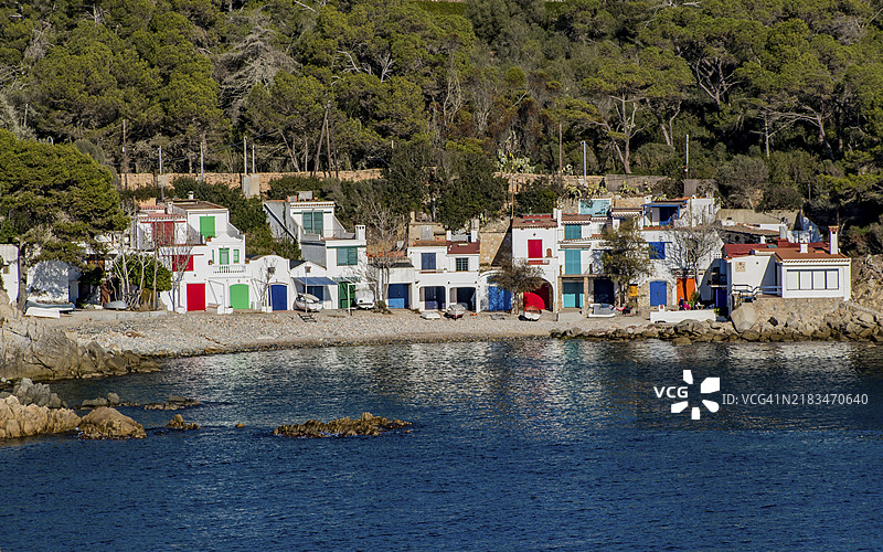 色彩斑斓的海边村庄，房屋俯瞰着岩石海岸，四周环绕着森林，阿尔格尔湾，布拉瓦海岸，加泰罗尼亚，西班牙，欧洲图片素材