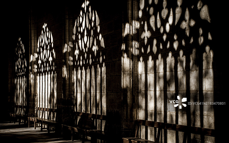 哥特式拱门在石墙上投射出复杂的阴影，下面有长椅，莱里达大教堂，回廊，阴影，西班牙，欧洲图片素材