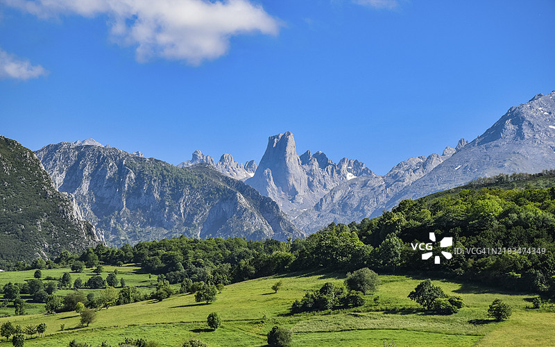 一幅风景如画的景象，展现了郁郁葱葱的绿田和壮丽的山脉，蓝天白云下的乌里耶卢山，欧洲西班牙皮科斯德欧洲。图片素材