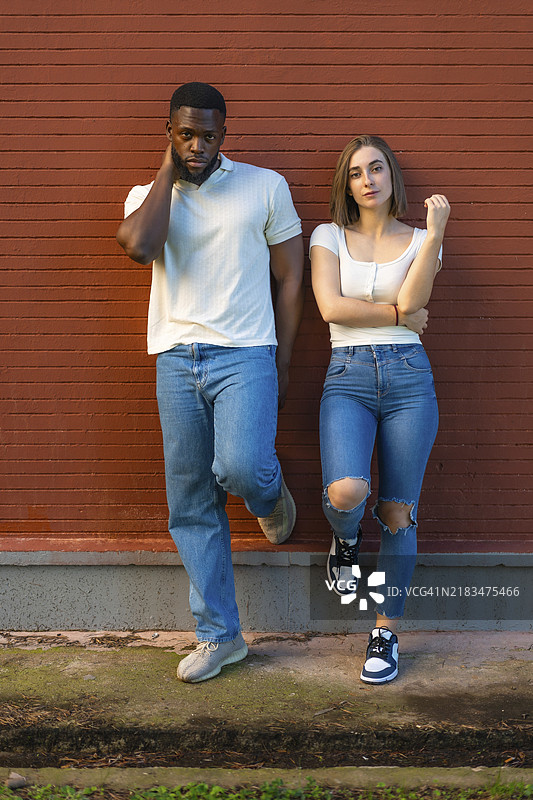 多种族模特穿着牛仔服装，靠在城市墙上，竖版全身照片图片素材