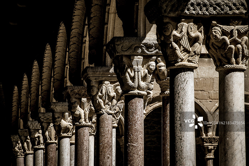 中世纪的石柱,雕刻精美,拱门错落,营造出阴暗而华丽的建筑场景,位于西班牙加泰罗尼亚的里波尔修道院,罗曼式风格。图片素材