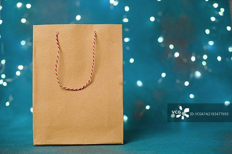 蓝色背景上的花环灯装饰的牛皮纸袋图片素材