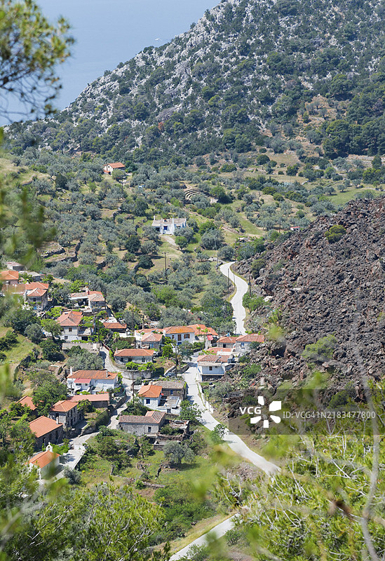 红顶山村与绿色环境沿着蜿蜒的道路,凯梅尼乔拉,火山景观,梅萨纳半岛,阿戈利斯,萨罗尼克群岛,伯罗奔尼撒,希腊,欧洲图片素材