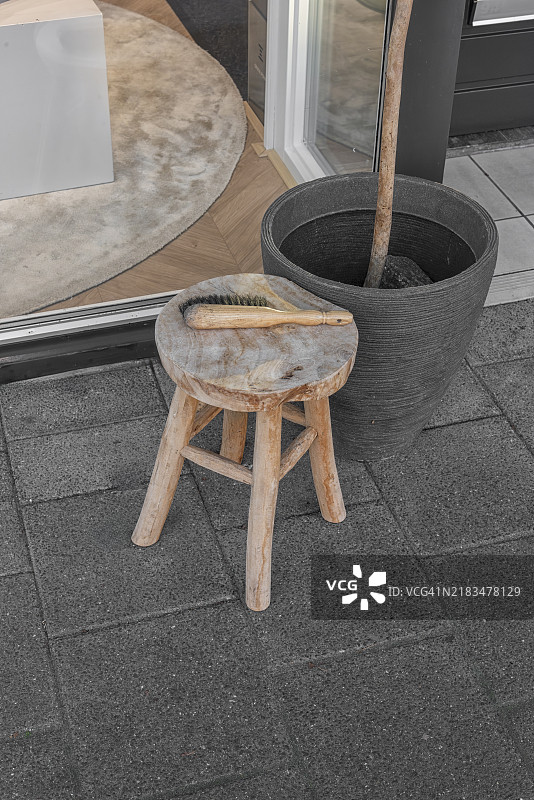 户外有一个棕色木凳，上面放着一把木刷，旁边是一个灰色花盆。图片素材