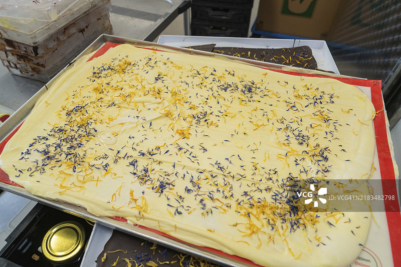 白巧克力上装饰着黄色和蓝色花瓣的特写，Burch Schokolade生产，Haselstaller Hof，德国，欧洲图片素材