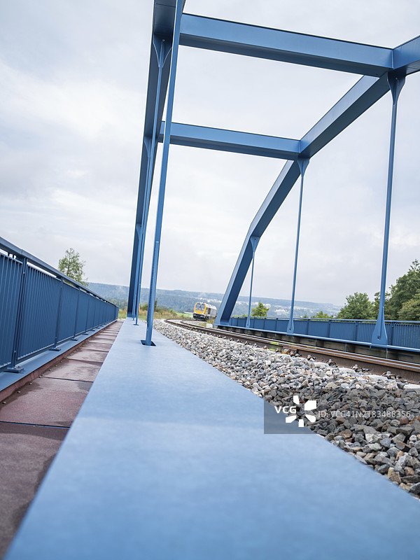 远处有一列火车的蓝色铁桥和铁轨,赫尔曼·黑塞铁路的轨道建设,铁路运输,卡尔夫,黑森林,德国,欧洲图片素材