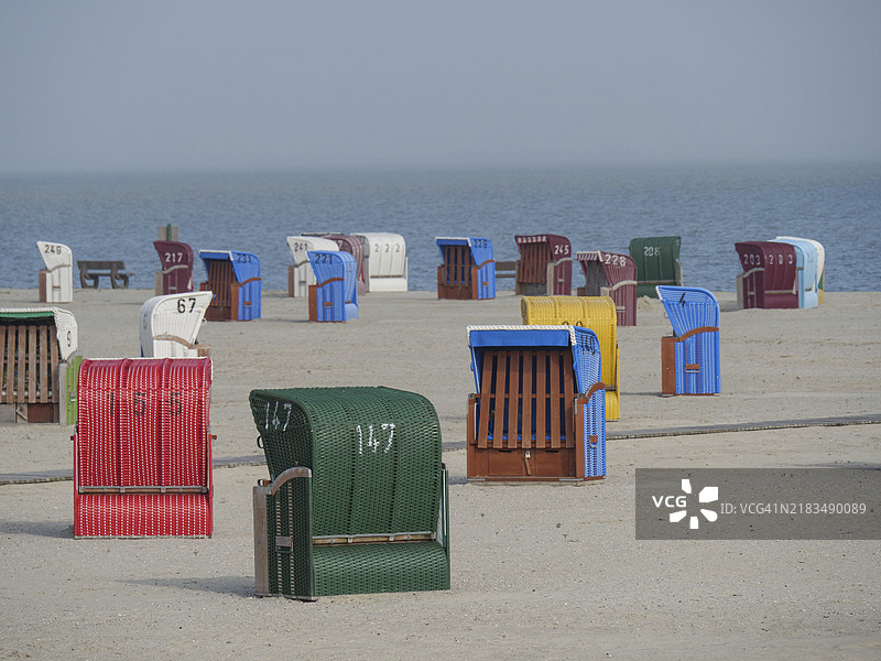不同颜色的沙滩椅在宁静的海滩环境中，内斯梅尔，北海，德国图片素材