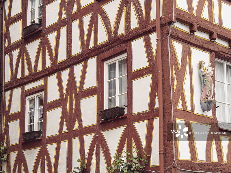 德国莱茵兰-普法尔茨州美因茨的半木结构建筑，红色支柱和墙面浮雕展示宗教人物。图片素材