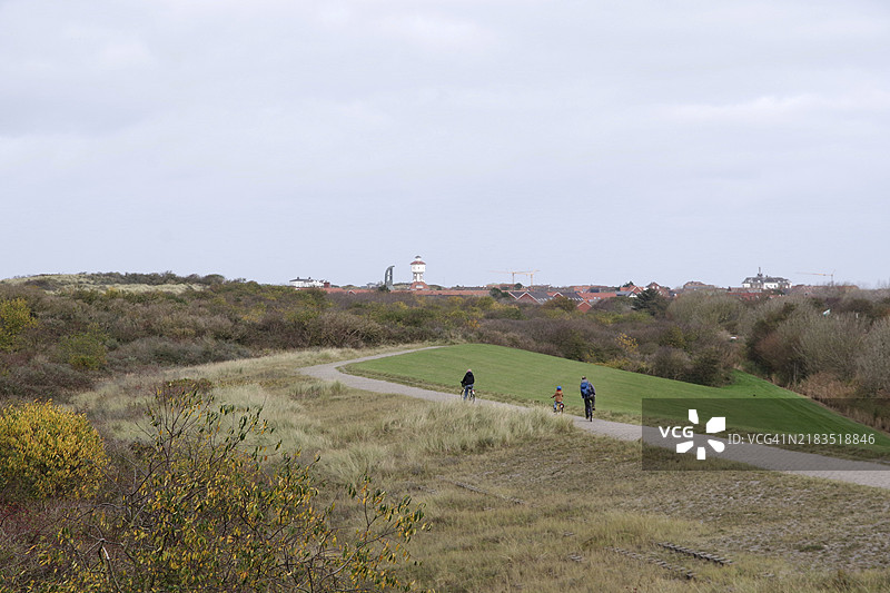 秋季在朗根奥格的沙丘景观，游客骑自行车前往市中心，德国下萨克森州瓦登海国家公园的朗根奥格。图片素材