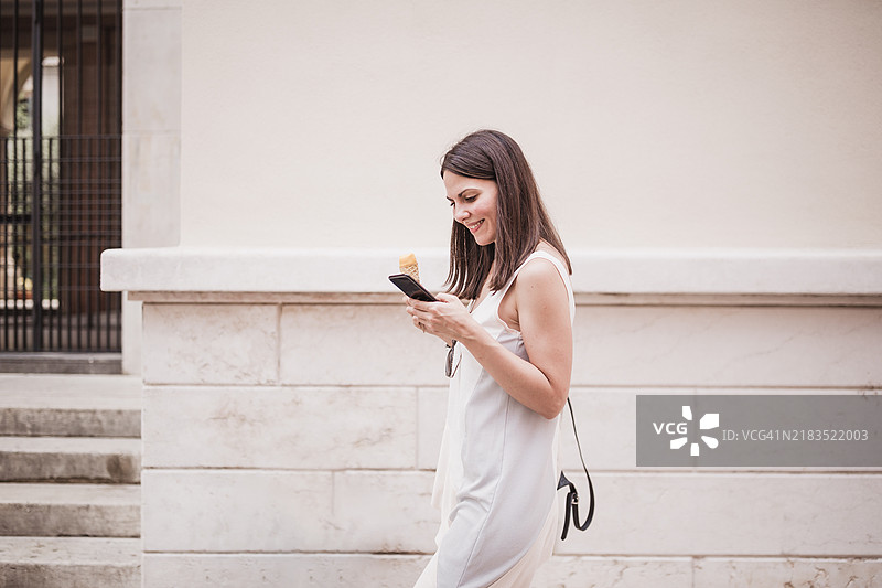 女人一边使用智能手机一边享受冰淇淋图片素材
