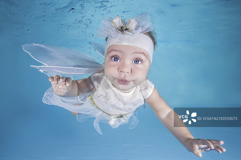 小女孩穿着仙女服装在游泳池里潜水图片素材