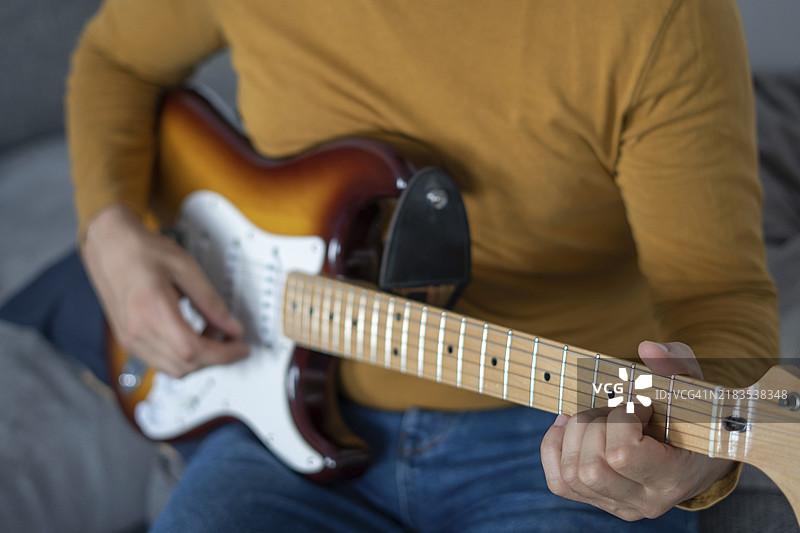 在家里弹吉他的年轻男孩，留着胡子图片素材
