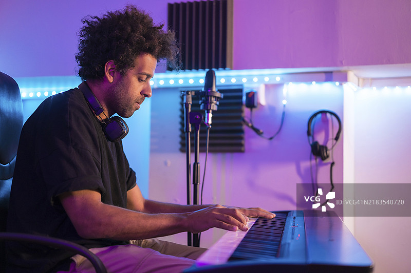 侧面视角的音乐制作人在霓虹灯下的录音室中创作新专辑图片素材