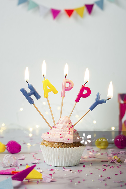 正面视角的生日杯子蛋糕，上面点燃了蜡烛图片素材