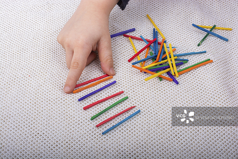 孩子在白色背景上玩彩色木棍，激发创造力图片素材