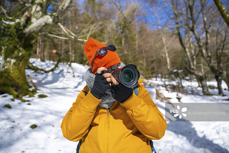 摄影师在雪山中背着背包拍摄冬季照片图片素材