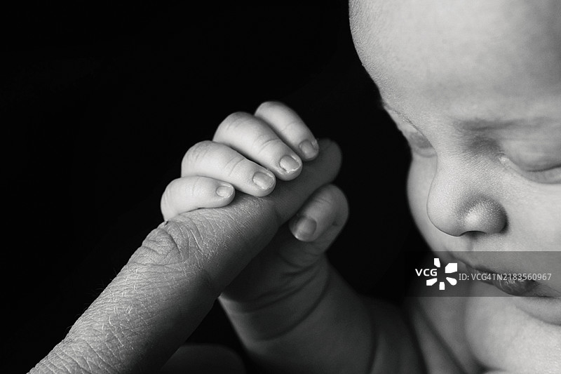 新生女婴握着爸爸的手指图片素材
