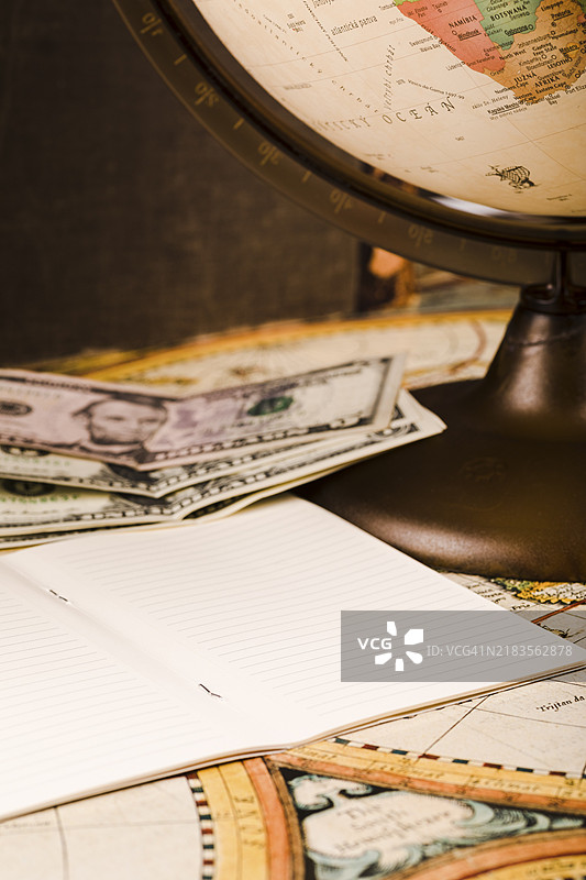 特写的笔记本、钞票、地球仪和地图图片素材