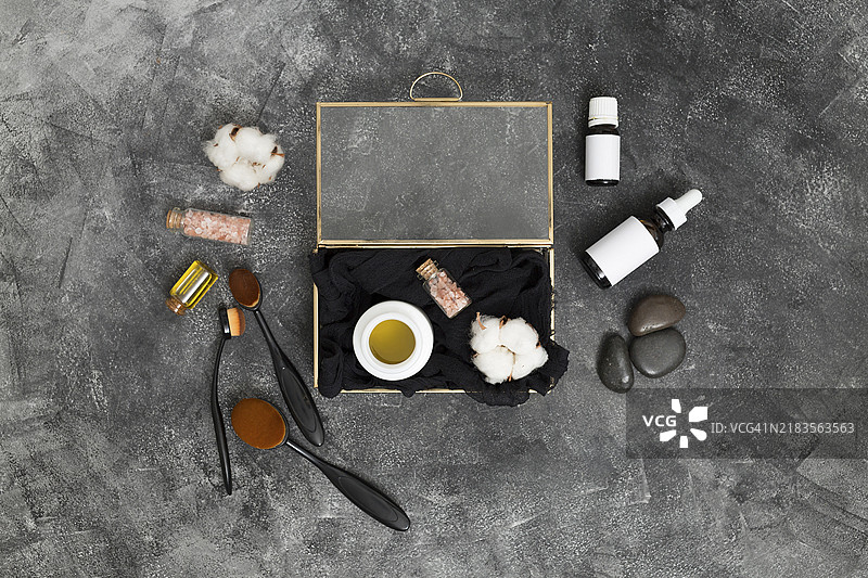 打开的盒子里有蜜桃色的喜马拉雅盐棉签和化妆品，背景为混凝土黑色。图片素材