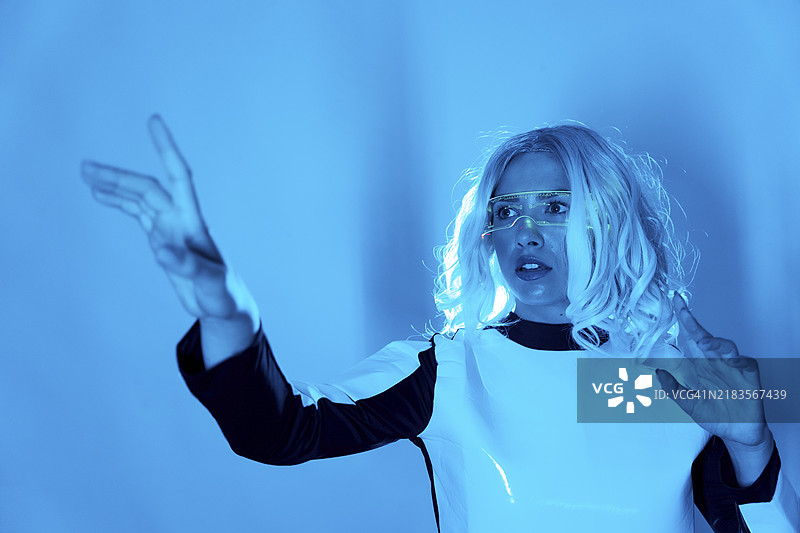 未来概念，未来世界中的年轻女孩佩戴眼镜，蓝色背景，赛博朋克，虚拟现实图片素材