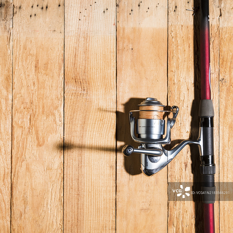 木桌上的钓鱼竿和钓鱼卷线器图片素材
