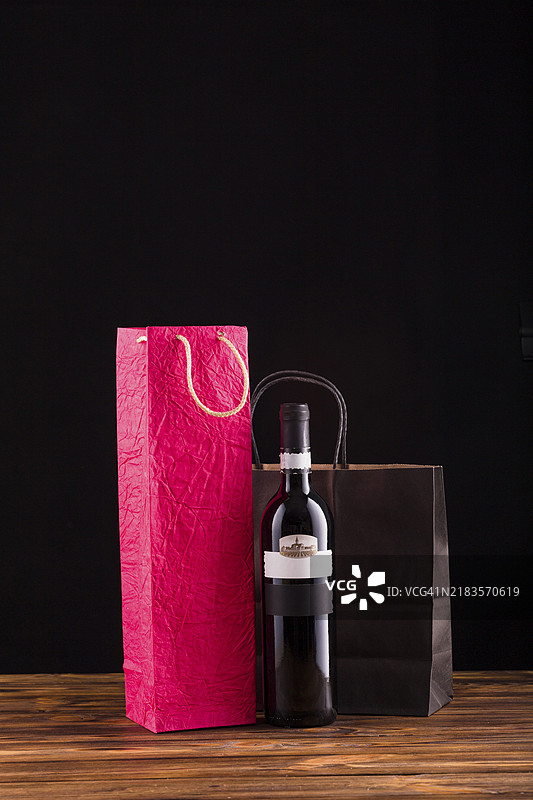 黑色酒瓶与精美纸袋放在木桌上图片素材