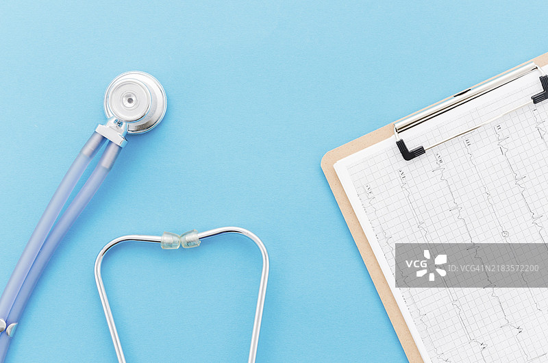 从上方俯视听诊器与心电图纸报告，蓝色背景图片素材