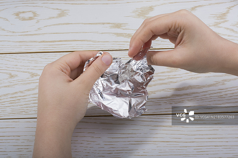 手撕心形铝箔，背景为木质表面图片素材
