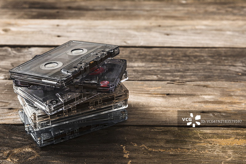 透明的卡带叠放在木质背景上图片素材