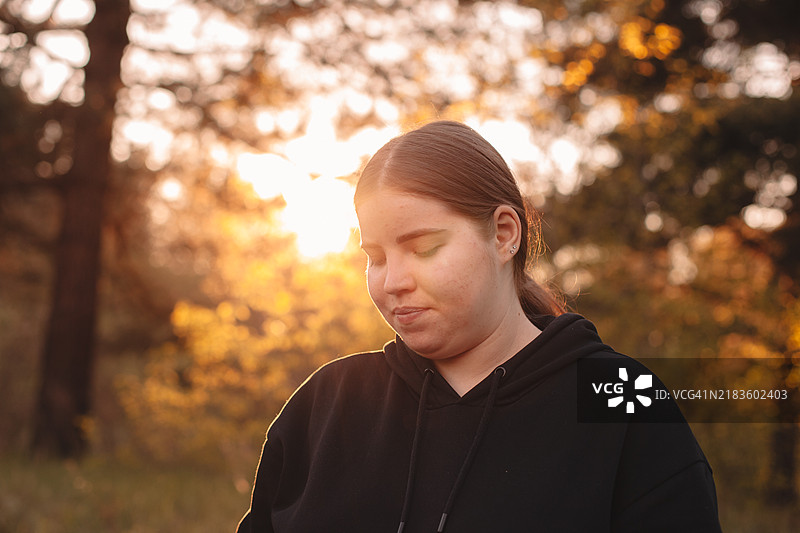 年轻女子在日落时分站在森林中肖像图片素材