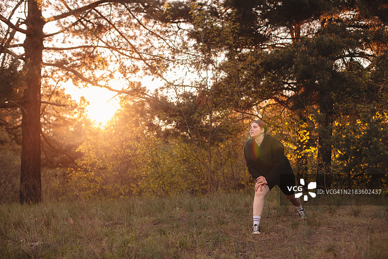 年轻女性在森林中做弓步运动图片素材