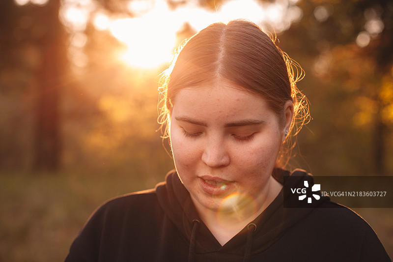 年轻女子在日落时分站在森林中肖像图片素材