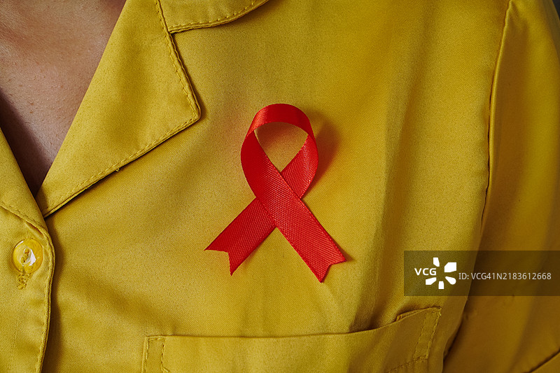女性胸前的红色艾滋病意识丝带图片素材